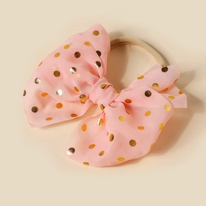 Detailed view of pink mesh bow headband with golden polka dots and soft nylon band