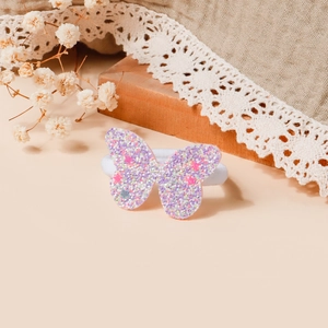Dettaglio dell'elastico per capelli a farfalla con paillettes e stelle su sfondo di lino