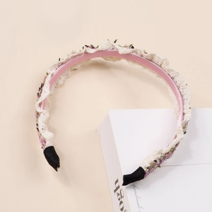 Détail du serre-tête fille en dentelle avec doublure en satin rose et broderie florale