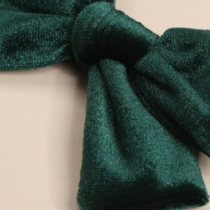Close-up of soft dark green velvet bow hair accessory showing premium woven texture