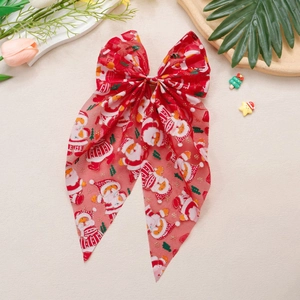 Détail du nœud de Noël en résille rouge avec imprimé Père Noël et longs rubans