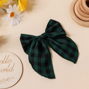 Détail du nœud papillon en coton à carreaux verts et noirs sur un fond pêche chaleureux
