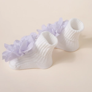 Détail de chaussettes bébé en tricot blanc avec grande fleur en tulle lavande superposée