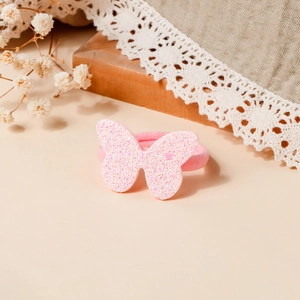 Dettaglio di un elastico per capelli con farfalla di paillettes rosa su sfondo decorativo