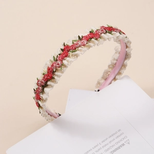 Détail de motifs floraux rouges brodés sur un bandeau en dentelle de couleur crème