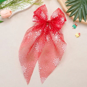 Détail de la pince à cheveux nœud de Noël en maille rouge avec flocons et paillettes dorées