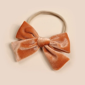 Detailed close-up of handmade velvet bow headband for girls in warm caramel color