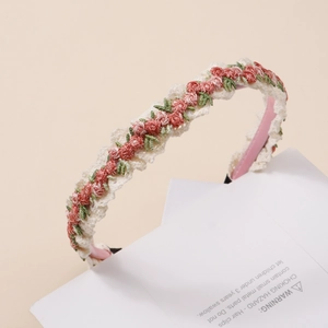 Gros plan détaillé du serre-tête en dentelle ivoire avec des roses brodées et feuilles vertes