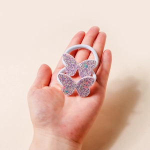 Dettaglio di due elastici a farfalla glitterati con paillettes viola e blu scintillanti in mano