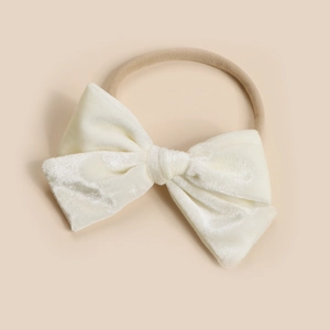 Detail of cream velvet bow on a soft nude nylon headband for infants and babies