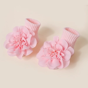 Détail de chaussettes bébé roses avec de grandes fleurs en tissu 3D et maille côtelée