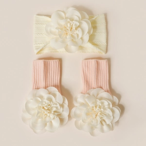 Détail d'un bandeau bébé beige et de chaussettes roses avec de grandes fleurs en tissu