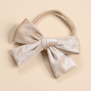 Detail of soft velvet bow baby headband with high-elastic nylon strap in champagne gold