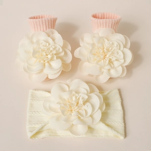 Détail de chaussettes et bandeau tricotés pour bébé avec de grandes fleurs 3D en tissu