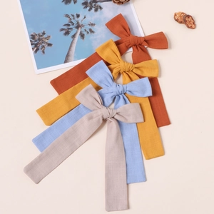 Detailansicht von Baumwoll-Schleifen-Haarspangen in Orange, Gelb, Blau und Beige