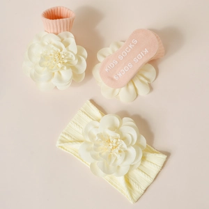 Détail d'un ensemble de bandeau et chaussettes bébé avec fleurs 3D et semelles antidérapantes