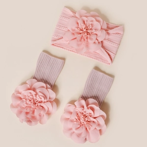 Vue détaillée du bandeau et des chaussettes en tricot rose pour bébé avec fleurs en 3D