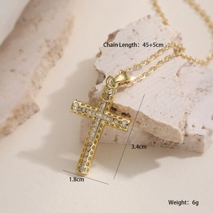 Vue macro d'un pendentif croix plaqué or 18 carats avec zircons sur pierre texturée