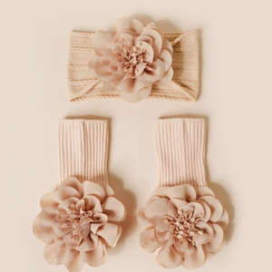 Détail du bandeau et chaussettes bébé tricotés avec grandes fleurs en mousseline rose