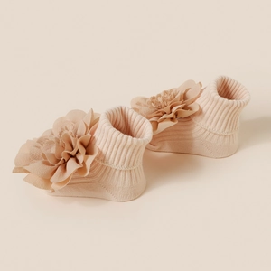 Détail de chaussettes tricotées pour bébé avec fleurs 3D multicouches rose tendre