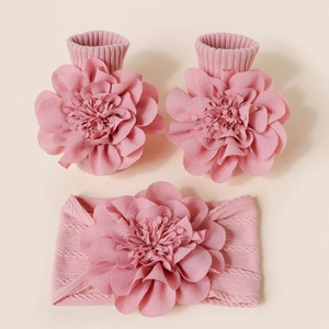Détail de l'ensemble bandeau et chaussettes roses pour bébé avec grandes fleurs tricotées