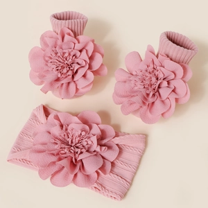 Détail de chaussettes et bandeau bébé en tricot rose avec grandes fleurs en tissu