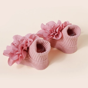 Vue détaillée des chaussettes tricotées roses pour bébé avec grandes fleurs décoratives
