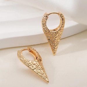 Boucles d'oreilles créoles dorées géométriques avec finition martelée sur soie blanche