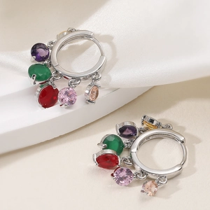 Créoles en argent avec zircons multicolores sur un fond élégant en soie blanche