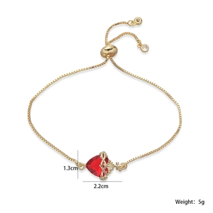 Détail macro du bracelet à chaîne dorée avec gemme de cœur rouge et cadre de flammes