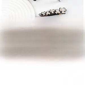 Detail shot of beige flower hair clip with pearl centers and elegant black outlines