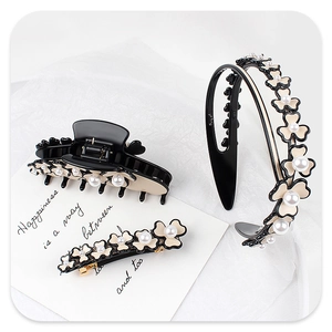 Detail view of beige acetate floral hair clips and headband with pearls and gold hardware