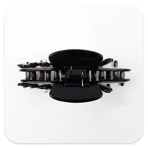 Detail of black acrylic hair claw clip featuring a 3D flower and white artificial pearl