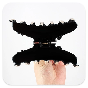 Detail of a large butterfly hair claw clip with black resin finish and beige accents