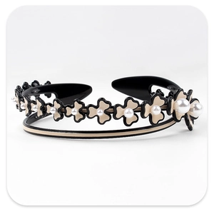 Detailed close-up of a floral headband with cream petals and pearl centers on black resin