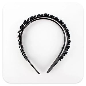 Close-up of a double-layered black headband with floral accents and faux pearls