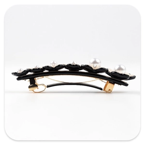 Detail of elegant black floral hair claw clip featuring centered white pearls and gold metal base