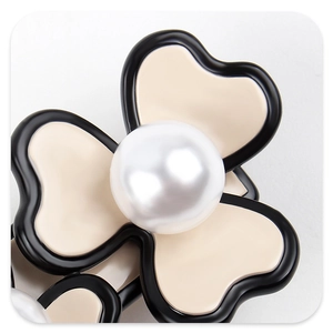 Detailed macro view of a vintage beige acetate flower hair claw with a large pearl center