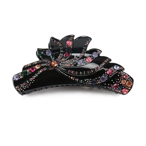 Détail d'une grande pince à cheveux noire avec strass colorés et bords ondulés élégants