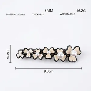Detail showing acetate hair claw clip with six white flowers and pearls, size 9.8cm long