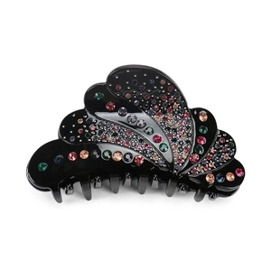 Macro shot of large black acrylic claw clip with colorful rhinestones on white backdrop