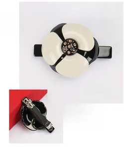Détail de la pince à cheveux camélia en acétate avec cristaux et clip à ressort métal