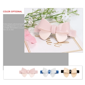 Detail of glitter finish resin bow hair clips in pink, light blue and creamy yellow