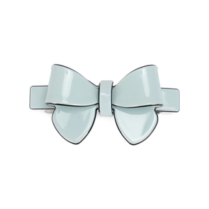 Detail of light blue glossy bow hair clip with black edges and metal spring mechanism