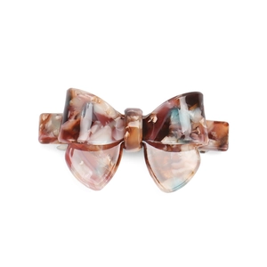 Close-up of a tortoiseshell acetate bow hair clip with colorful marble pattern and metal spring