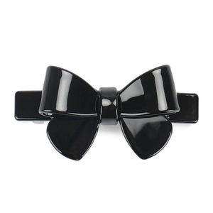 Close-up of a glossy black acetate bow hair clip with a sleek spring-loaded fastener