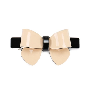 Detail of a beige and black dual-tone bow hair clip with glossy acetate finish