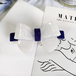 Detail view of the acetate bow hair clip with white marble pattern and blue base