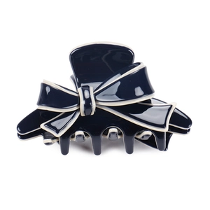 Dettaglio macro della pinza per capelli blu navy lucida con bordo a contrasto bianco crema