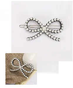 Détail d'une barrette nœud faite main avec perles blanches sur base en acétate